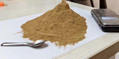 Heap of brown powder with a spoon and a scale.