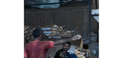 Two men in a warehouse with stacked bags.