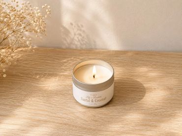 Lit scented candle on wooden surface with dried flowers.