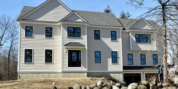 Newly constructed two-story house with beige siding and multiple windows.