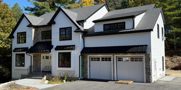 Modern two-story white house with black window frames and attached garage.