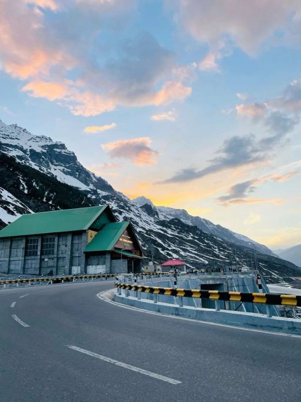 Mountain road with snow-covered peaks at sunset.