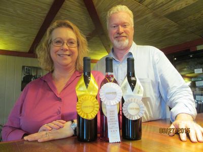 A picture of the owners of Chateau MerrillAnne, Emily and Kenny, posing with award winning wine.