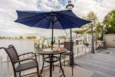 Outdoor patio with table, chairs, and umbrella overlooking a marina.