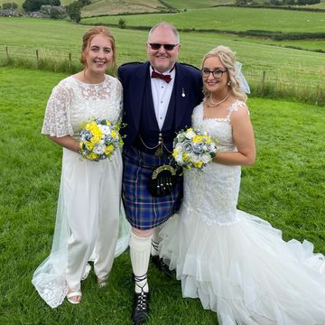 Same sex wedding couple with smiling celebrant in highland dress