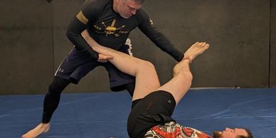 Two men practicing Brazilian Jiu-Jitsu in a gym.