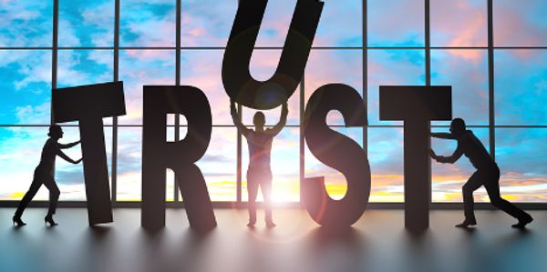 three people putting together the word trust