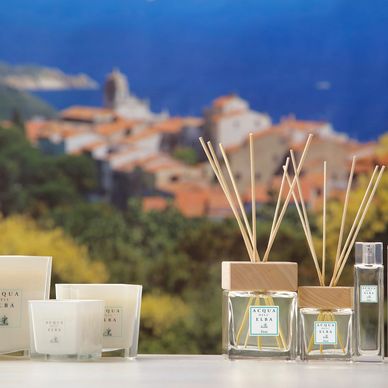 full range of acqua dell elba Home Fragrances with beautiful italian town in thebackground