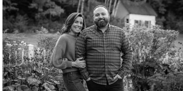 Couple smiling outdoors in a garden.