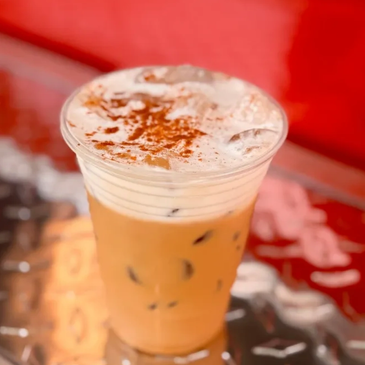 Iced coffee topped with foam and cinnamon.