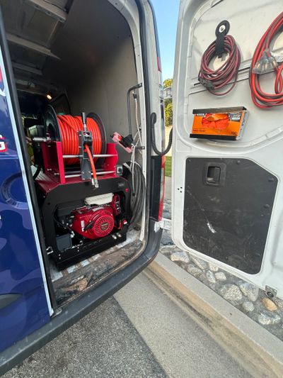 Open van door showing industrial hose reels and equipment inside.