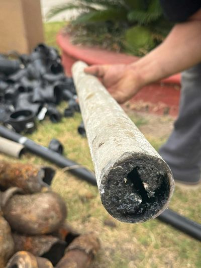 Close-up of a hand holding a corroded metal pipe with a hollow interior.