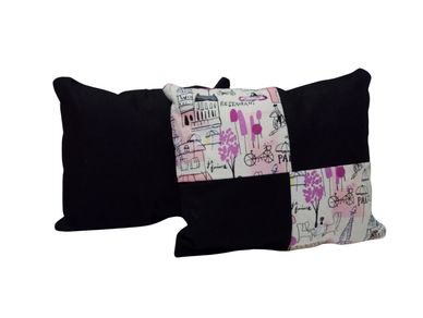 Two decorative pillows, one black and one patchwork with pink and black design.