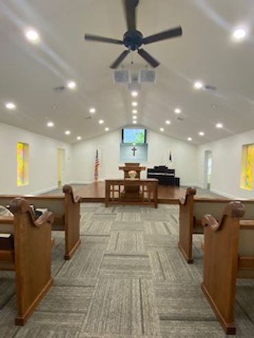 Interior of a small modern church with pews and a cross.