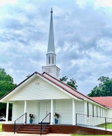 White church with tall steeple and red roof.