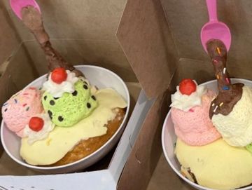 Two bowls of ice cream sundaes with cherries and spoons.