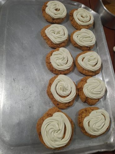 Oatmeal cookies with white icing swirls on a baking tray.