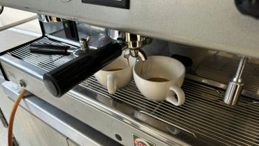 Espresso machine brewing coffee into two white cups.