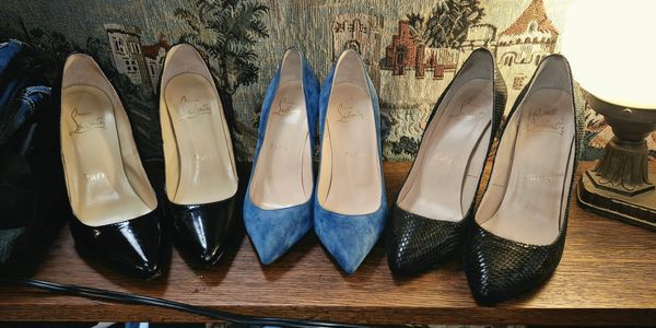 Three pairs of women's high heel shoes lined up on a wooden surface.