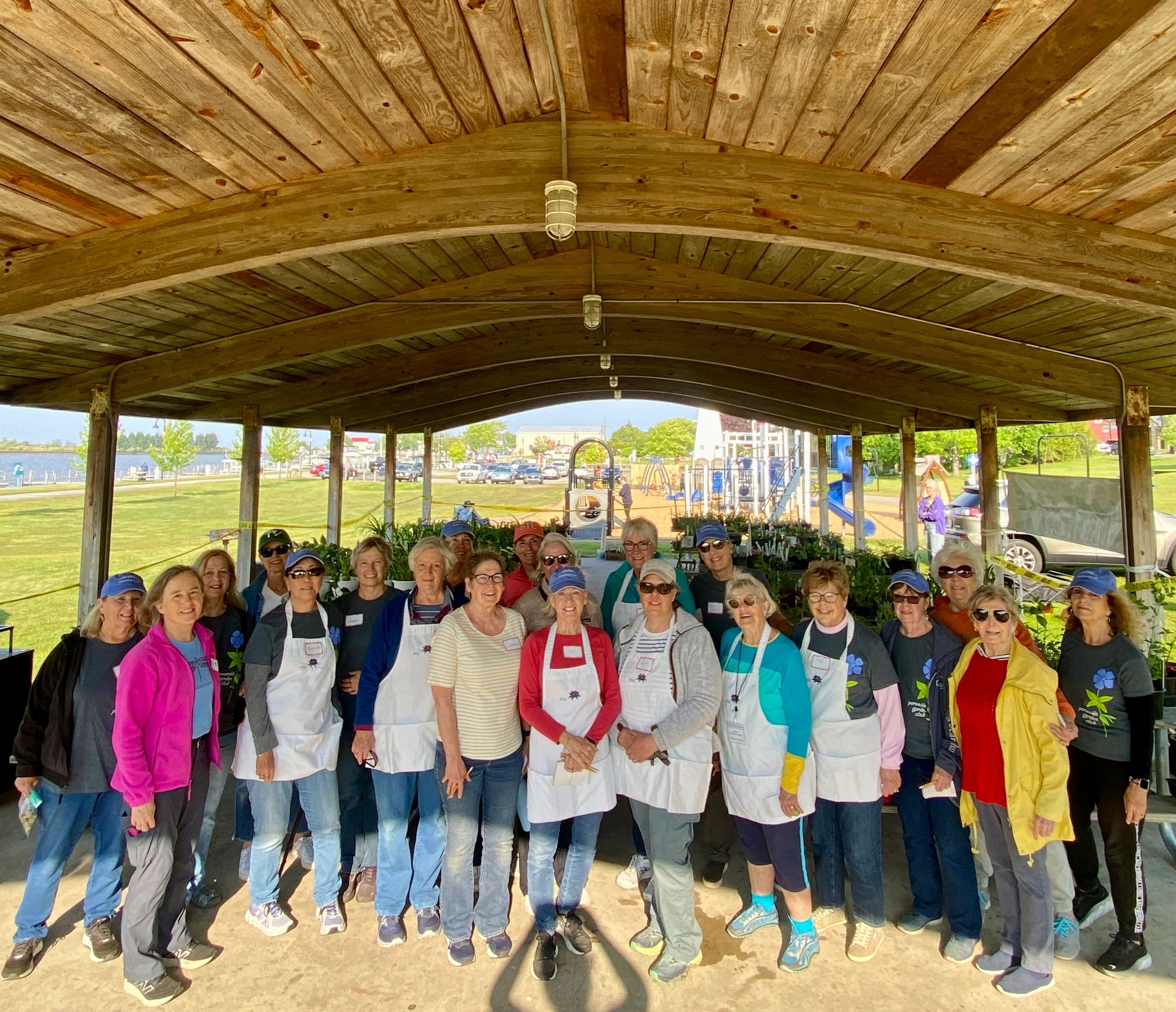 Group of volunteers posing under wooden pavilion at park.