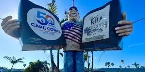 Statue of a man holding two signs, one celebrating 50 years of Cape Coral.