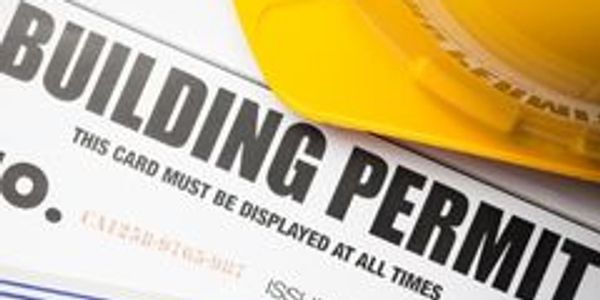 Close-up of a building permit with a yellow construction helmet.