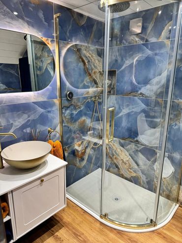 Blue and gold tiles with an offset quadrant shower, mirror and gold sit on basin on display