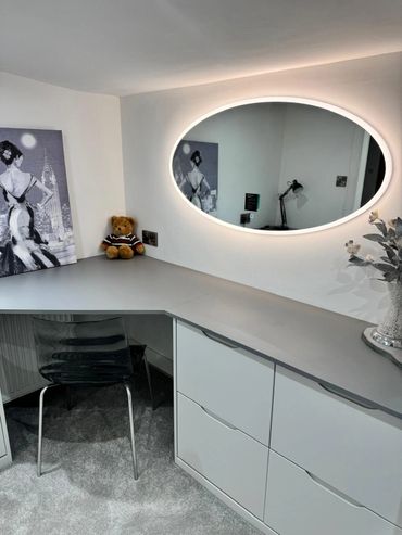 Bedroom display showing an illuminated mirror and cupboards in a matt grey colour