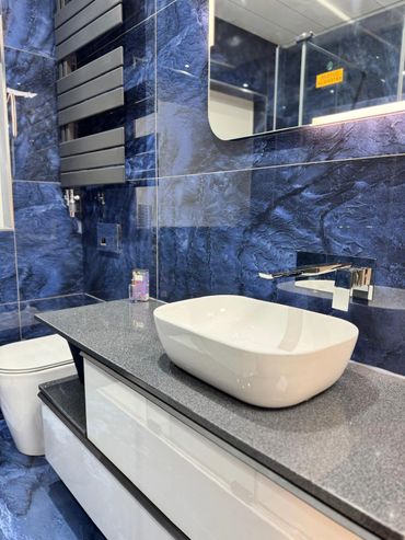 Picture of blue tiles on a wall with a white bathroom vanity unit with sit on basin