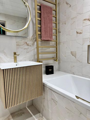 Modern gold marble tiles with fluted furniture a gold radiator and gold framed mirror