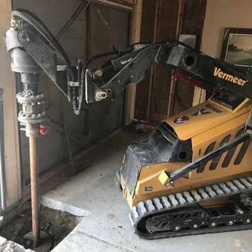 Vermeer mini skid steer with auger drill inside a garage.