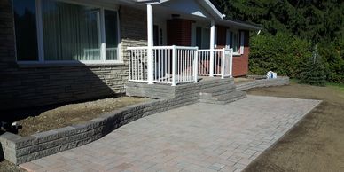 Interlocking stone entrance to house with stone garden beds and stone front porch with steps