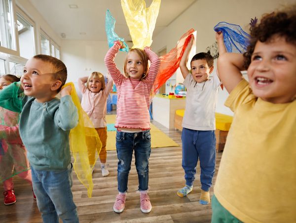 Children playing with colorful scarves indoors.