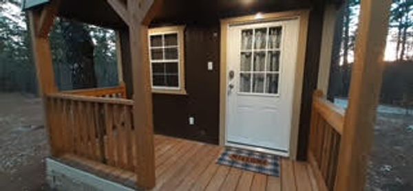Front porch of tiny cabin with white french door