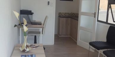 Small workspace with desk, chair, and vase with flowers.