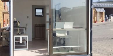 Modern office space with glass walls and white furniture.