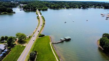 A scenic road runs between two bodies of water with boats scattered on the lake.
