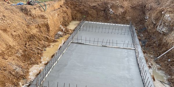 Construction site with concrete foundation and excavator.