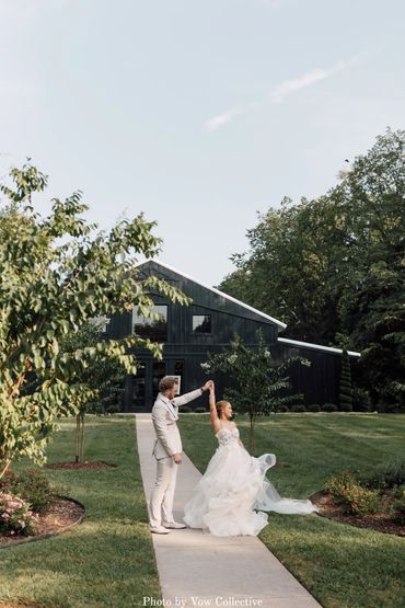 Newlyweds dancing in front of black barn. Wedding photography at The Barn at Firefly Lane Weddings.