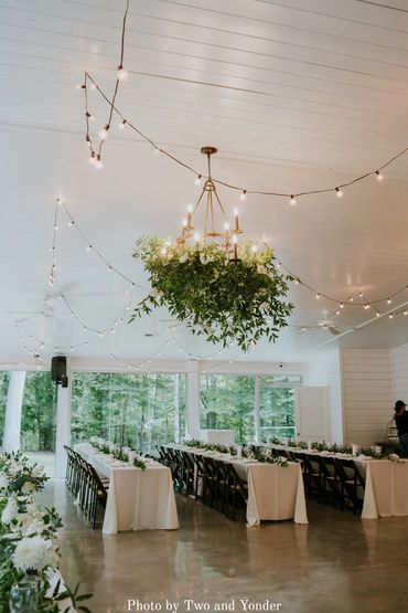 Lush greenery hanging from chandeliers during wedding dinner at the chapel reception hall.