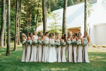 Bride and her bridesmaids in their bridesmaid dresses in front of the charming white chapel.
