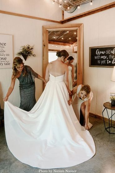 Mom of bride buttoning the bride's dress before ceremony in the bridal suite.
