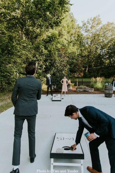Wedding guests enjoying a game of cornhole on the outdoor patio at Firefly Lane wedding venue.