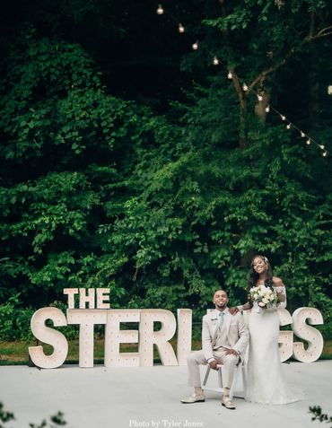Bride and groom in front of marque light up letters in the lawn at The Barn.