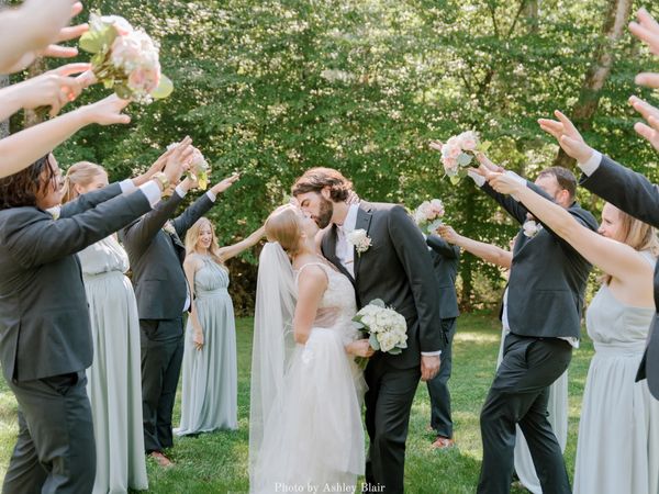 Something blue with blue bridesmaid dresses forming a bridal party tunnel for the bride and groom.