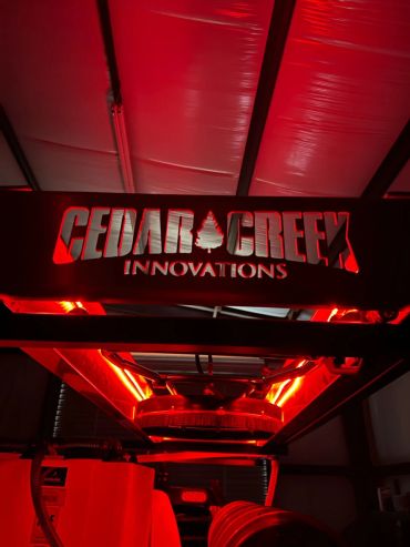 Red-lit Cedar Creek Innovations logo inside a vehicle or machine.