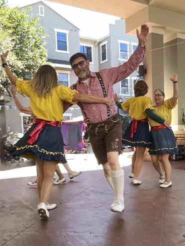 Man in lederhosen doing a Hungarian swing with arm raised.