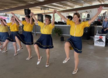 5 ladies with arms raised to bow.