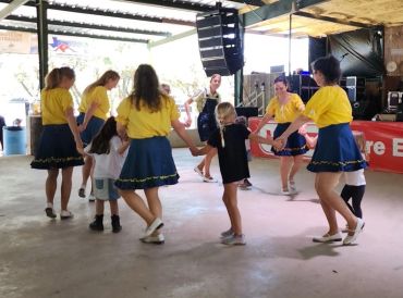 Adults and children dancing facing in toward each other in circle.