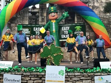 Dancers in Irish attire on decorated stage.